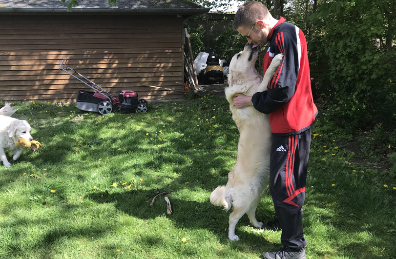 man in tracksuit with white dog on its hindlegs