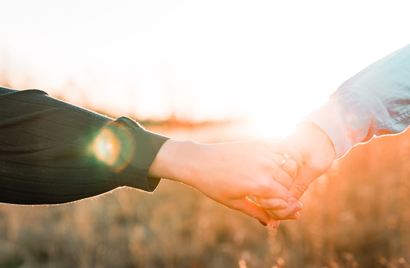 sexual-development-image holding hands with sunset behind